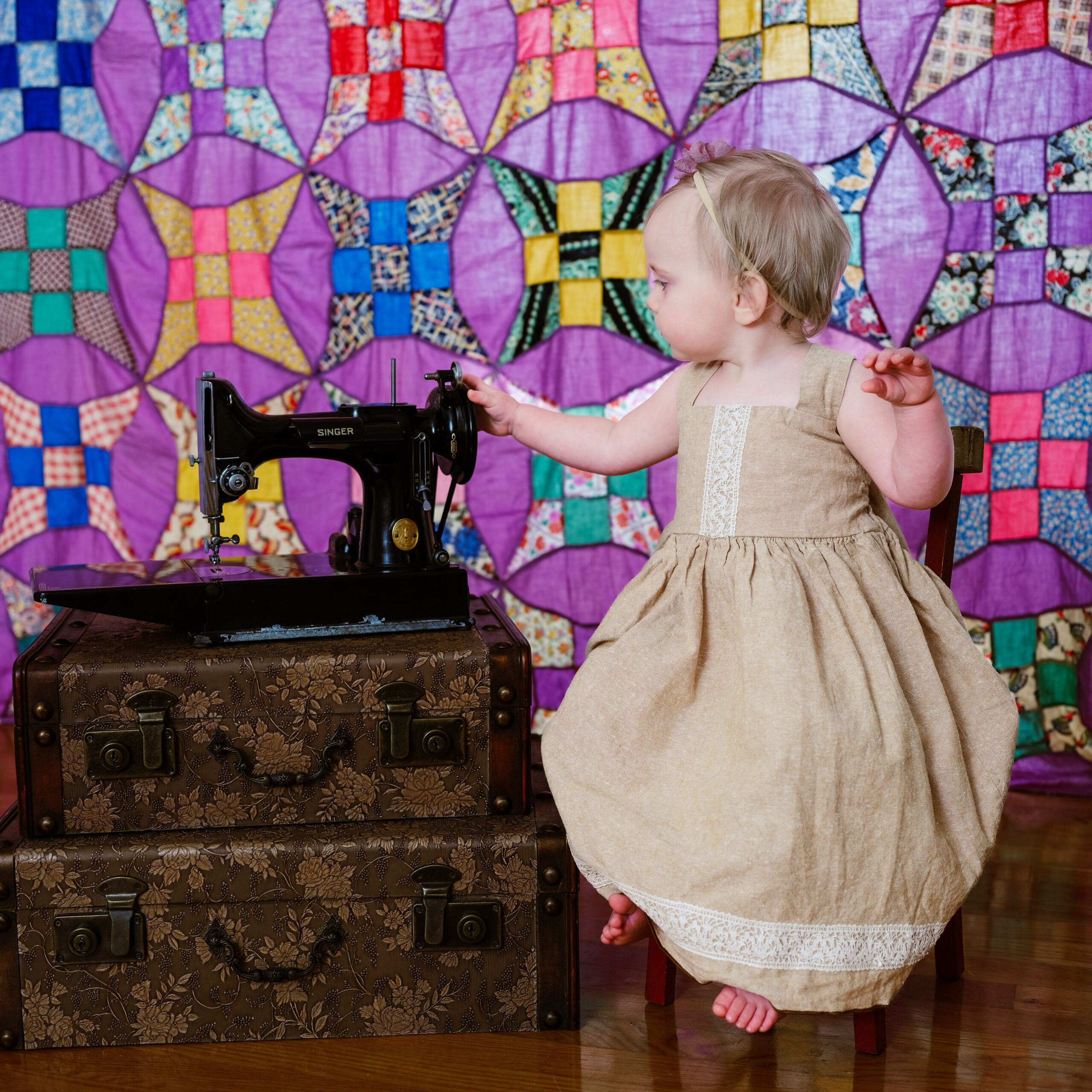 Toddler with Singer Featherweight sewing machine with a quilted backdrop